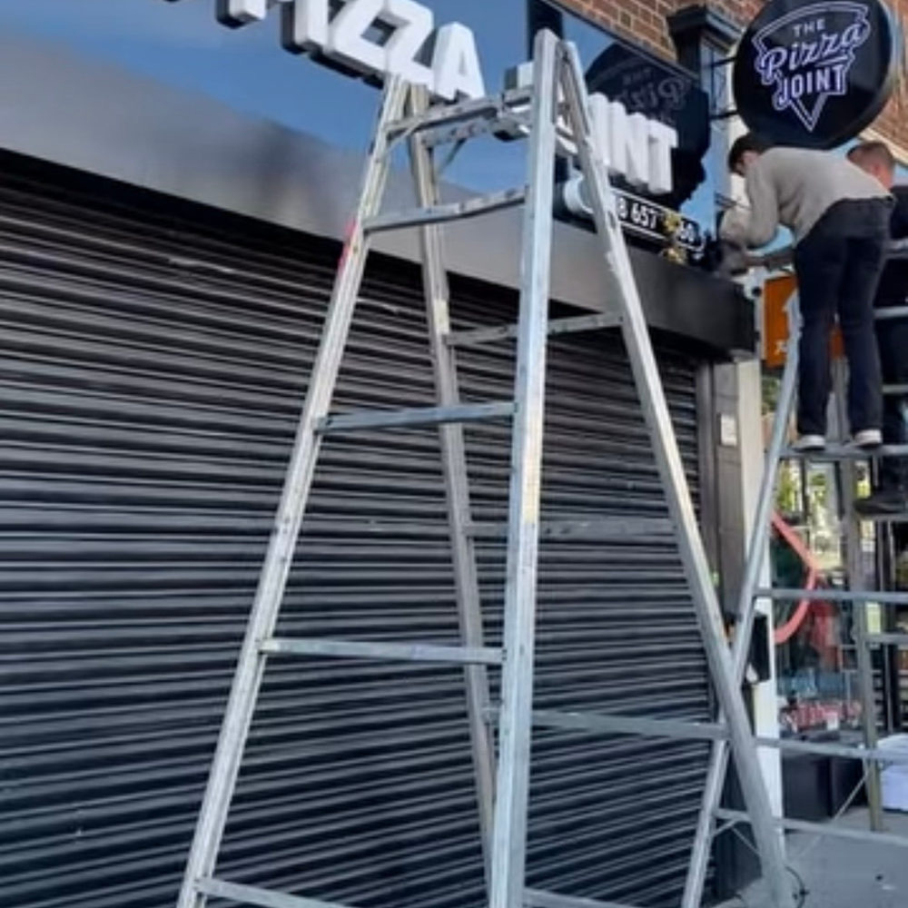 Installer fitting a shop sign